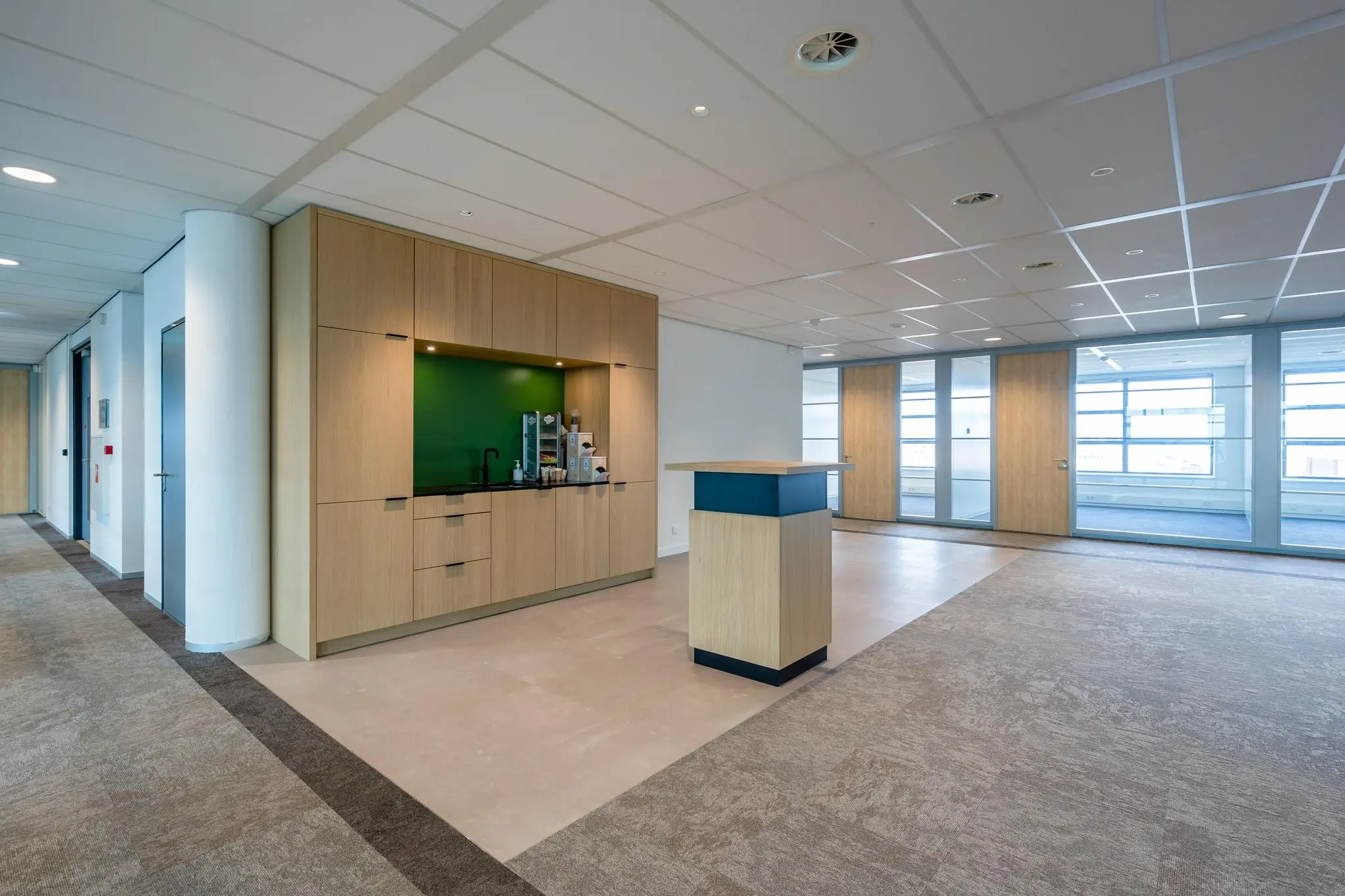 Moderne kantoorkeuken met koffieautomaat en houten afwerking aan de Fascinatio Boulevard.